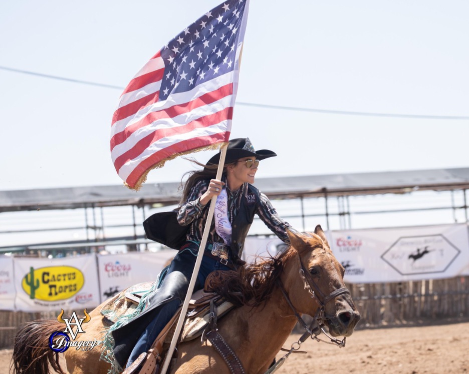 Student holds American flag while riding horse